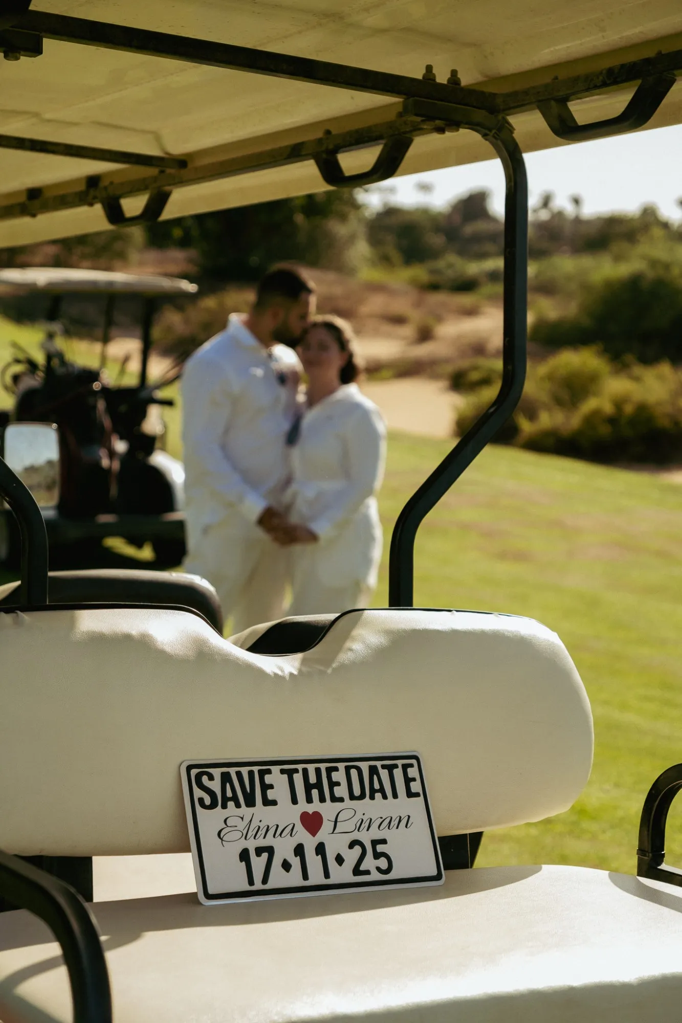 צילומי Save the Date בשדה גולף, שלט עם תאריך החתונה ומאחוריו זוג מתחבק